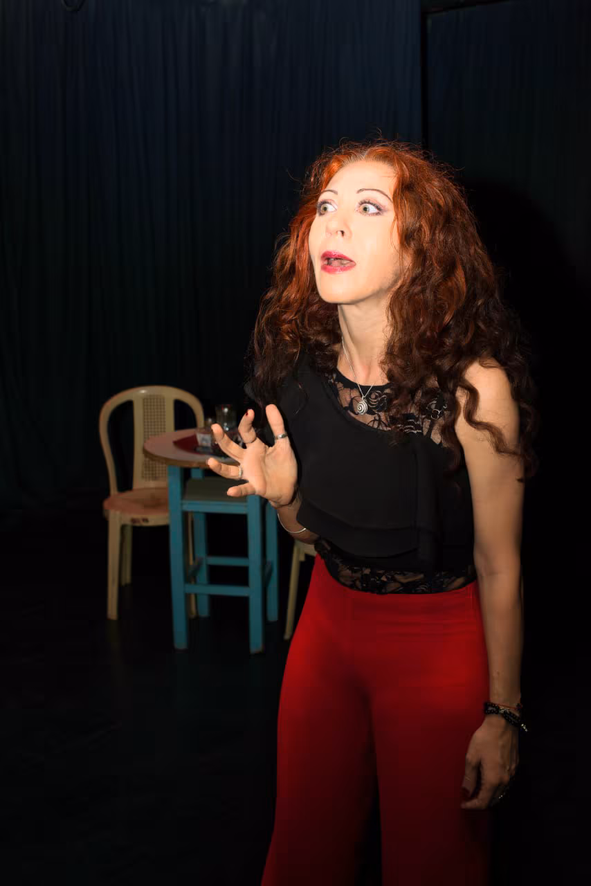 Eva ArtVision en escena de teatro, expresión sorprendida, con sillas de utilería de fondo